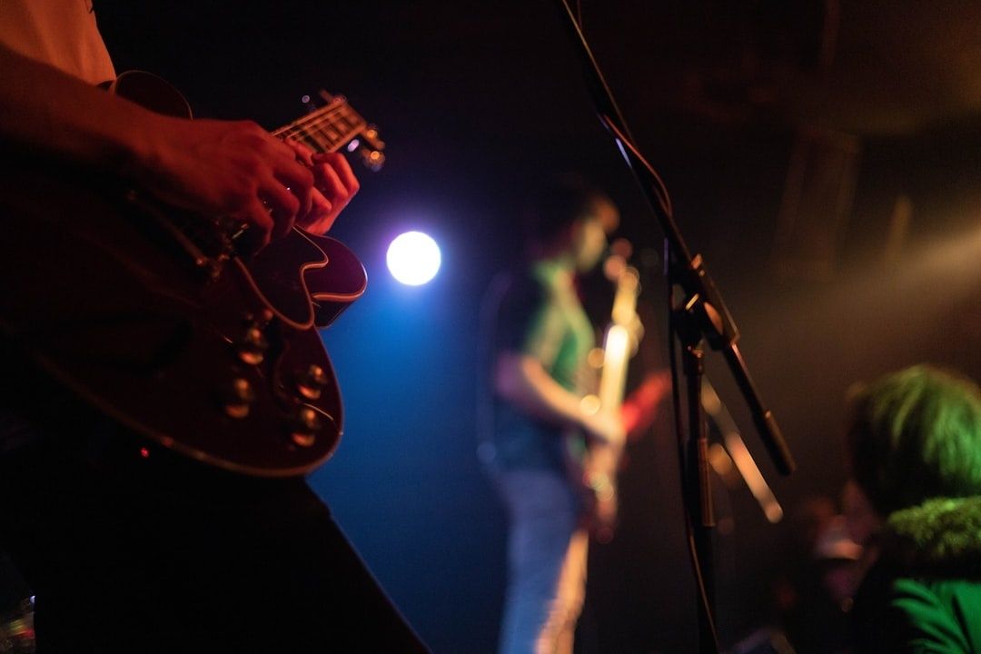Close-up of guitarist performing at a dimly lit small live show