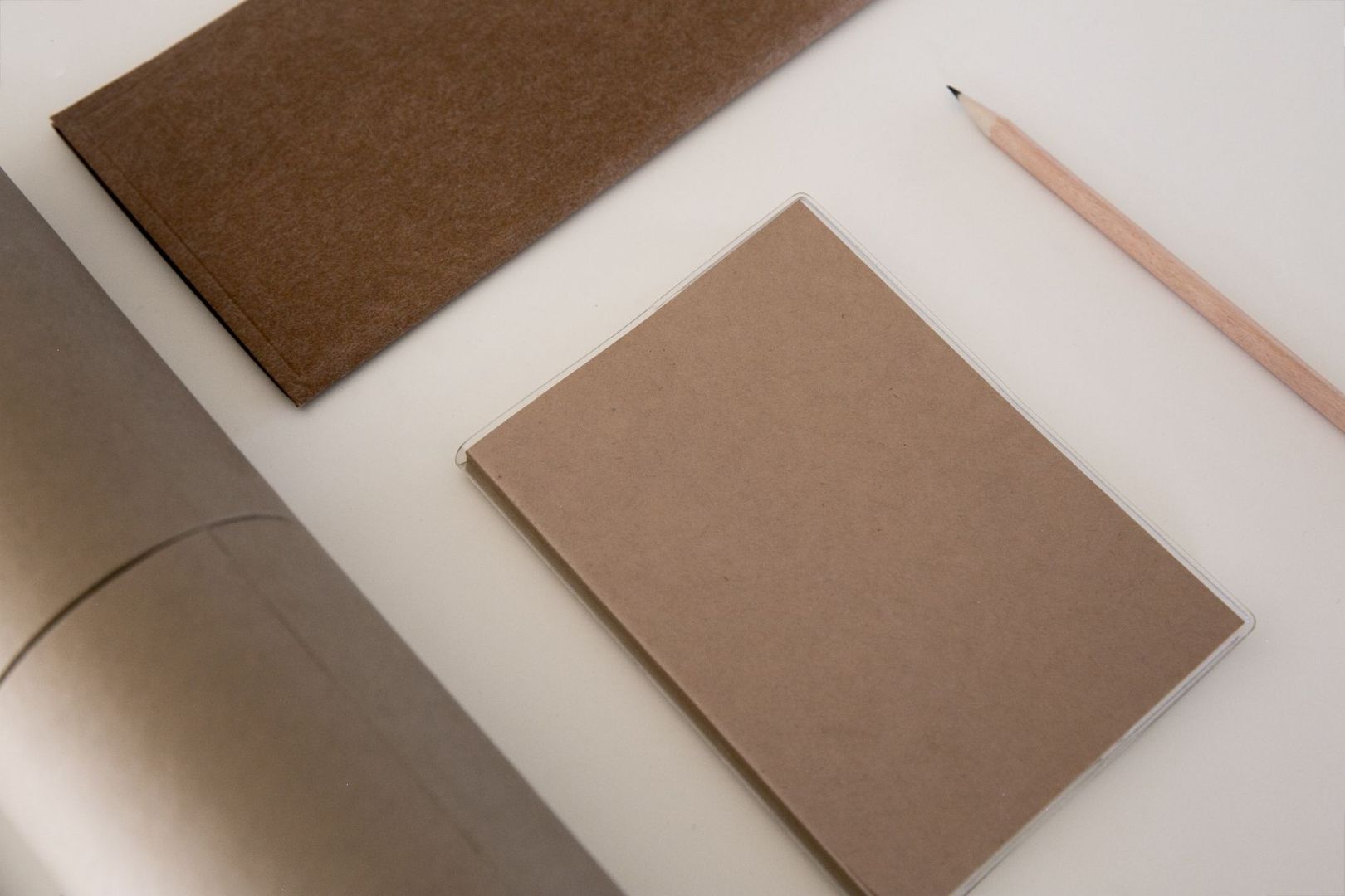 Brown blank notebooks and a sharpened pencil on a white desk